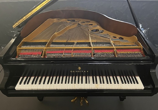  A grand piano with its lid open, revealing the intricate internal mechanics