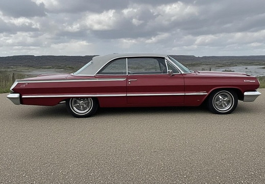 A classic, deep red two-door convertible car parked on an asphalt road. 