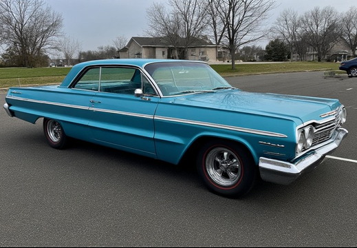 A bright turquoise two-door coupe, likely a Chevrolet Impala