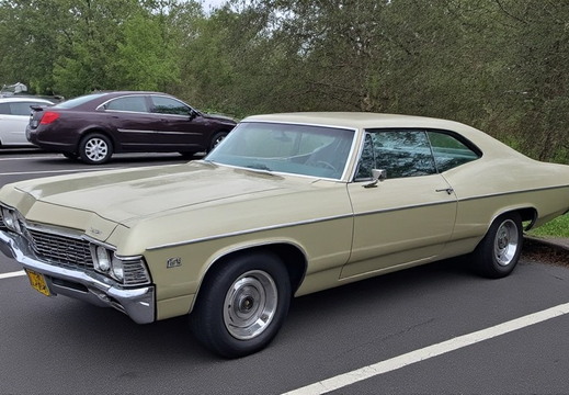 A vintage, light beige Chevrolet Impala coupe